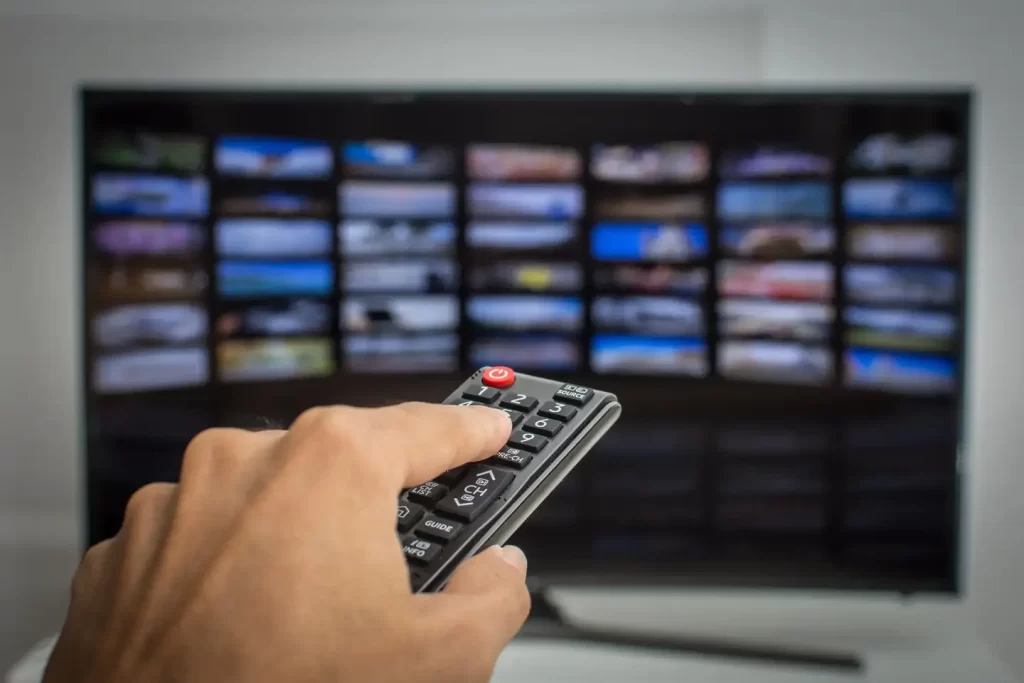 Hand using remote control to browse IPTV channels on Smart TV